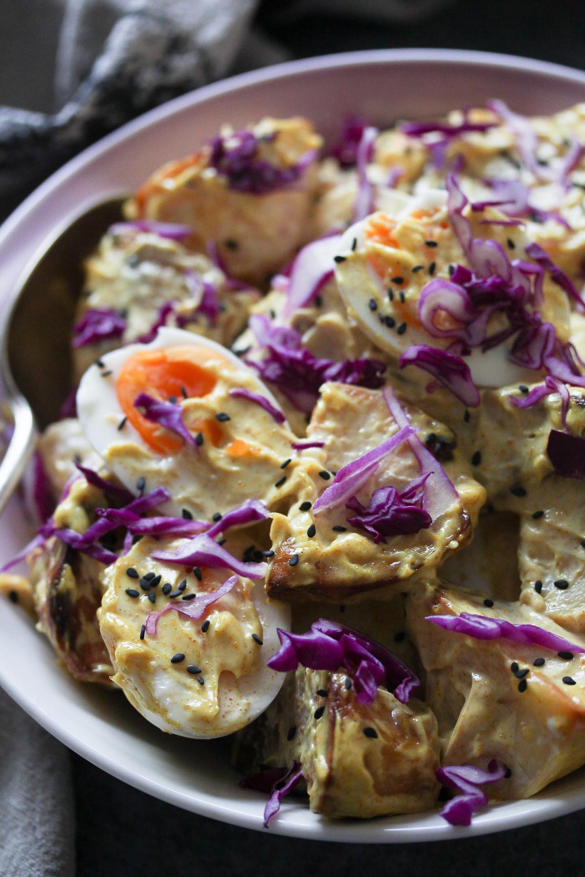 Japanese Curried Potato and Egg Salad, garnished with red cabbage, black sesame seeds and served in a bowl