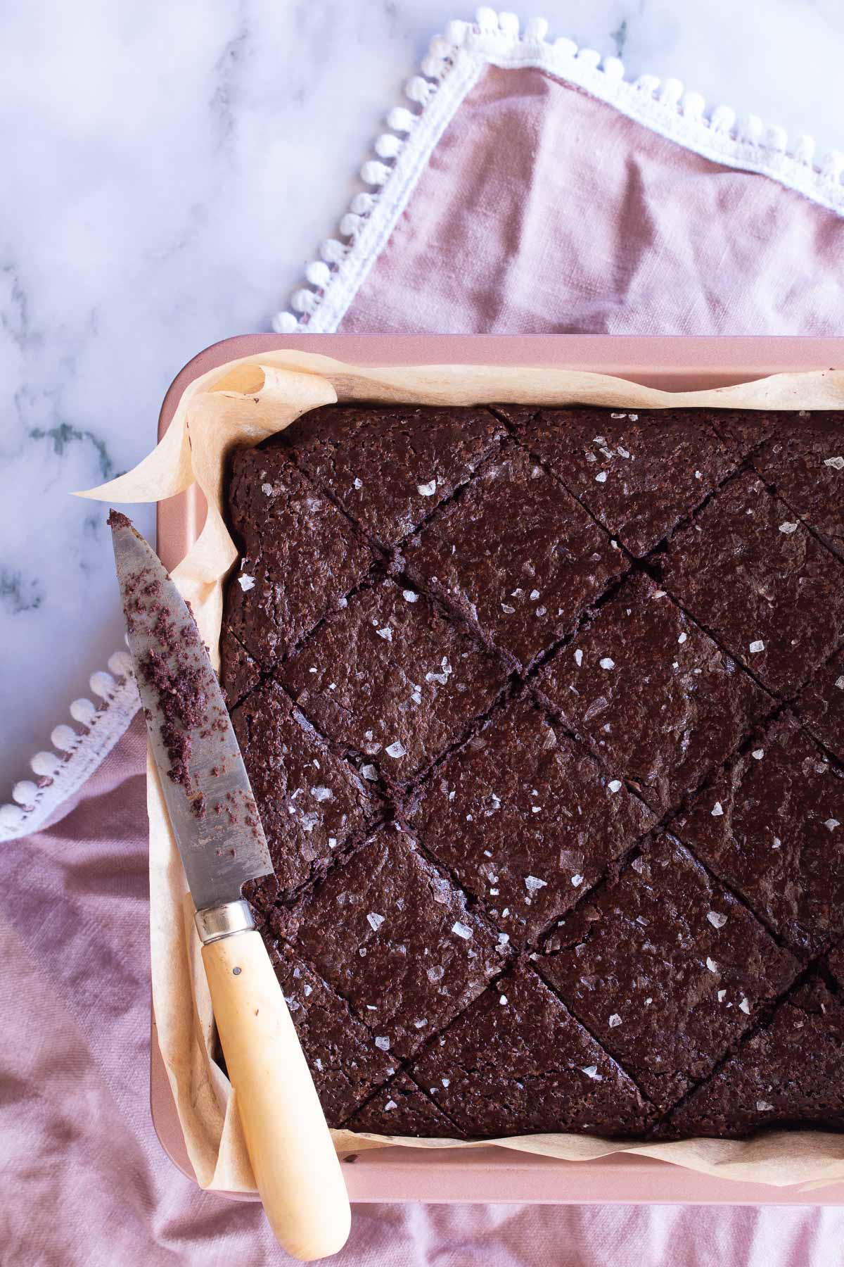 Miracle Flourless Brownies freshly cut in in a diamond shape and sprinkled with sea salt