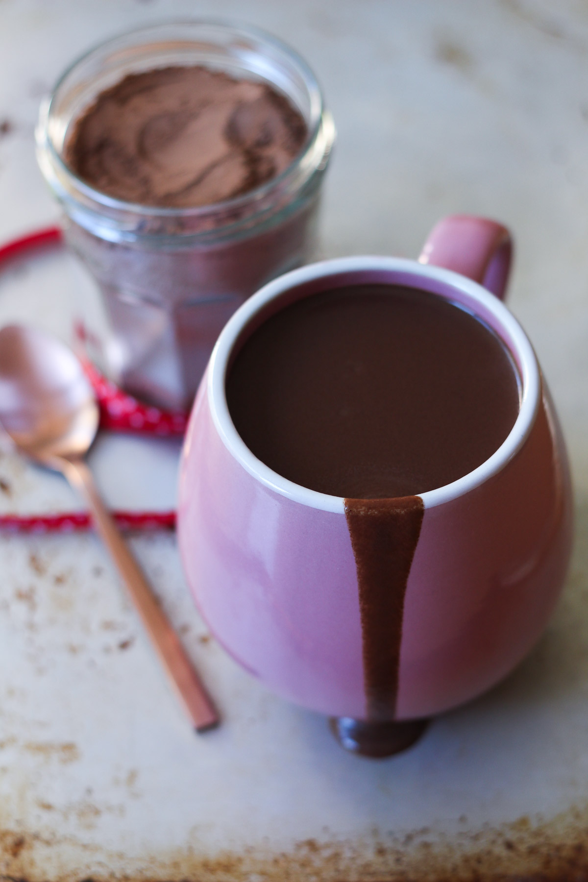 Luxe hot chocolate drizzling down a pink mug with hot chocolate mix in the background