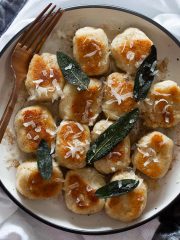 Ricotta gnocchi plated and garnished with crispy sage leaves and fresh grated parmesan