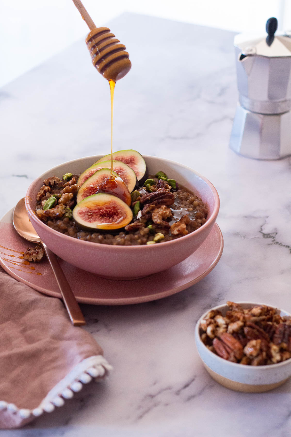 Drizzling honey over a bowl of Baklava Buckwheat Porridge served with figs and candied nuts