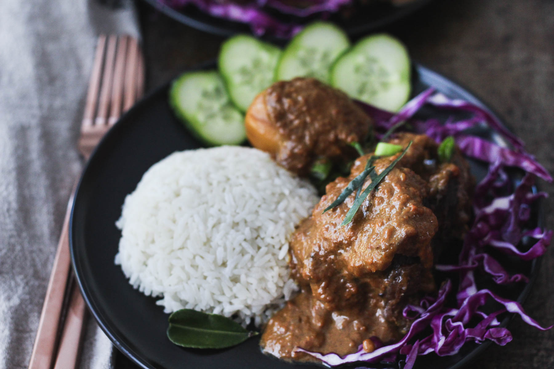 Beef Cheek Rendang served with white rice, sliced cucumbers and shredded red cabbage