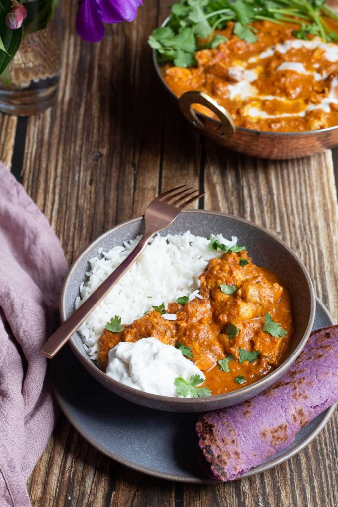 Bowl of delicious Dairy Free Butter Chicken served with purple flatbread and fluffy basmati rice